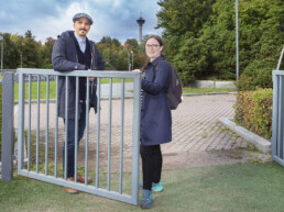 Mies ja nainen seisovat puiston portin takana, taustalla näkyy Näsinneula.